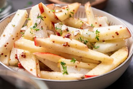Kohlrabi-Rohkost-Salat mit Apfel und Kresse auf einem tiefen Teller.