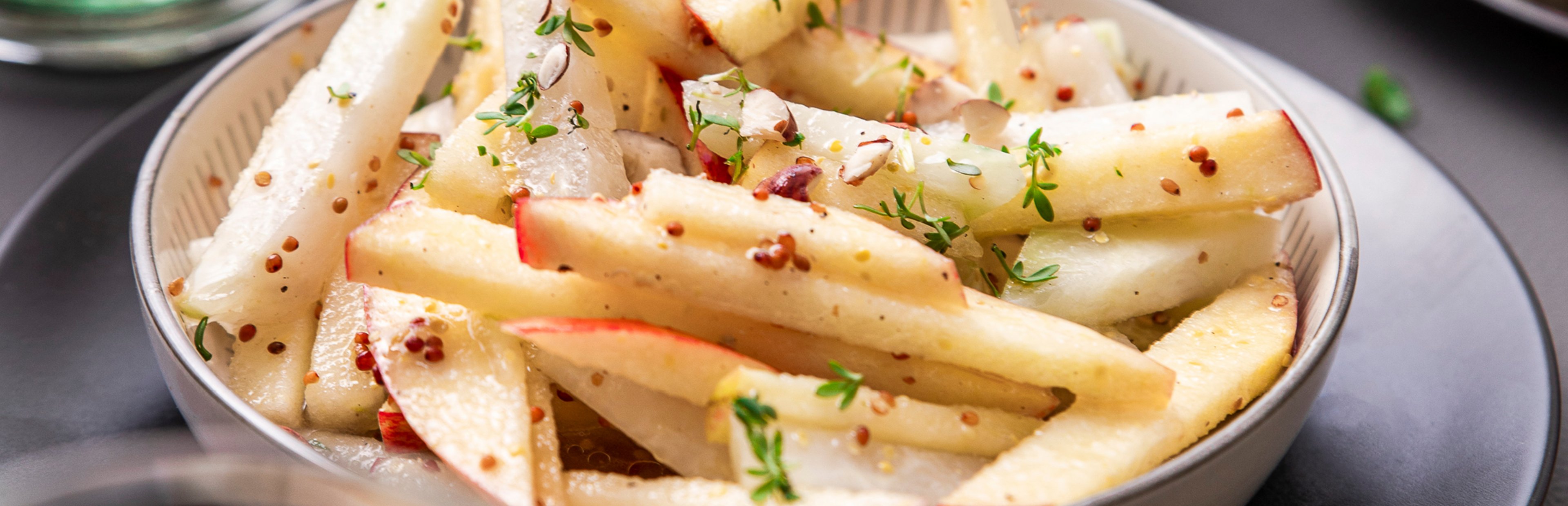Kohlrabi-Rohkost-Salat mit Apfel und Kresse auf einem tiefen Teller.