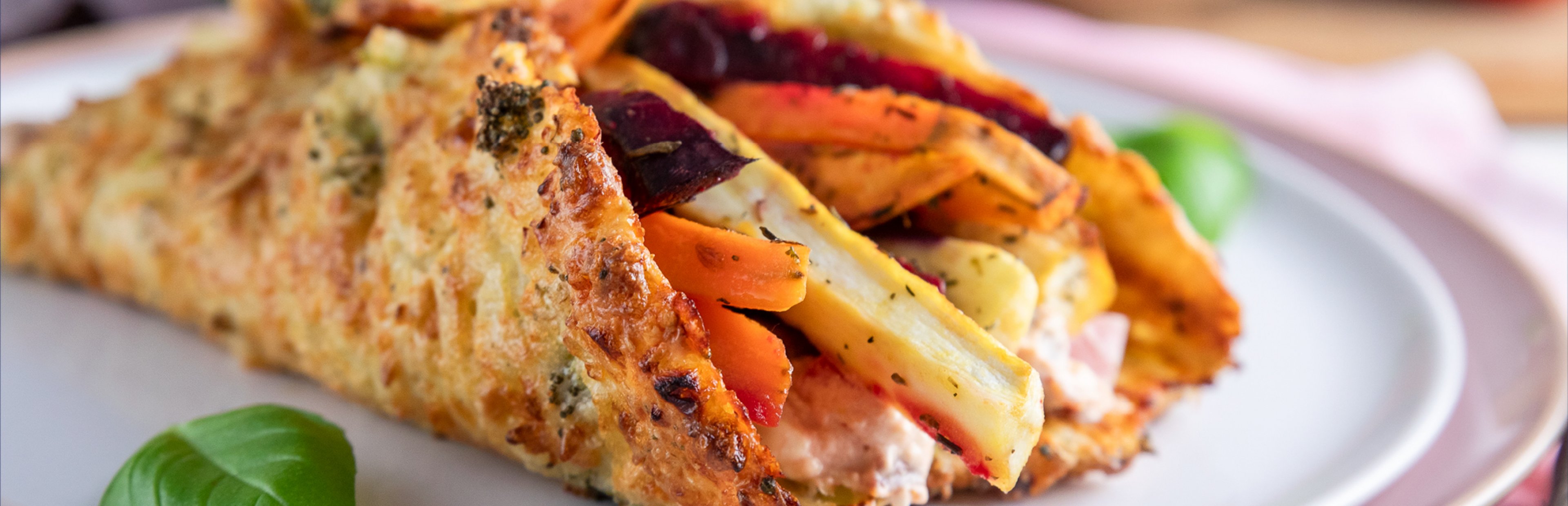 Ein Wrap aus Hüttenkäse gefüllt mit Ofengemüse, angerichtet auf einem weißen Teller.