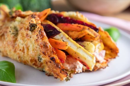 Ein Wrap aus Hüttenkäse gefüllt mit Ofengemüse, angerichtet auf einem weißen Teller.