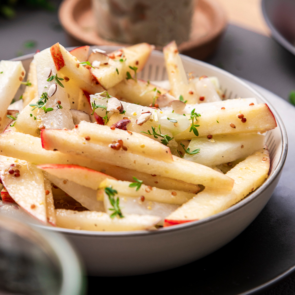 Kohlrabi-Rohkost-Salat mit Apfel und Kresse auf einem tiefen Teller.